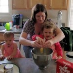 A mother making a cake with her two children