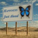 A large sign with the words 'Happiness Just Ahead the sign also has the image od a large Blue butterfly'