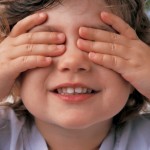 A small child covering her eyes with her hands.