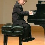 A small boy playing piano