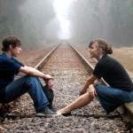 Boy and girl are sitting on a railway to have a nice talk.