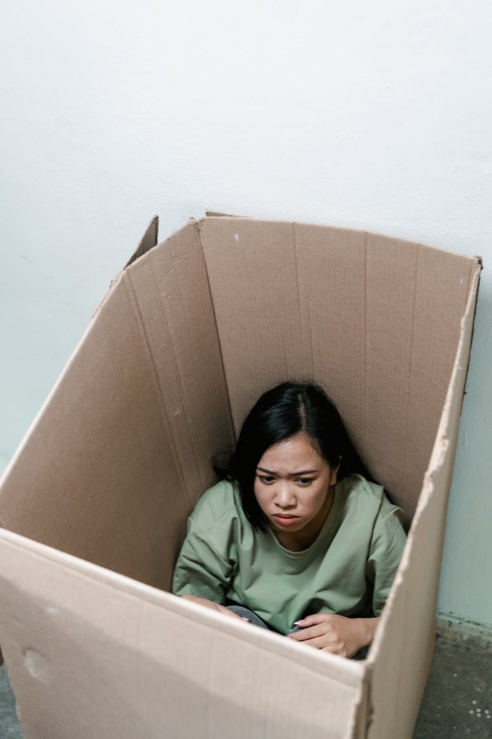A woman hiding in a box because of anxiety.