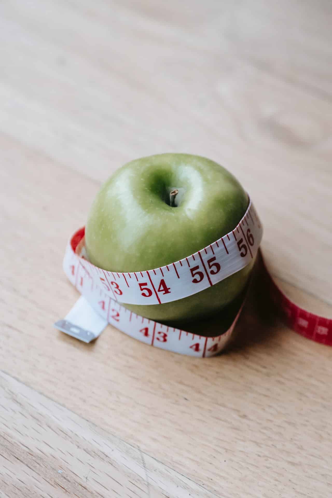 An apple wrapped with measuring tape.