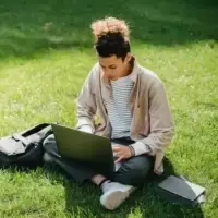 A man using a laptop in the park.